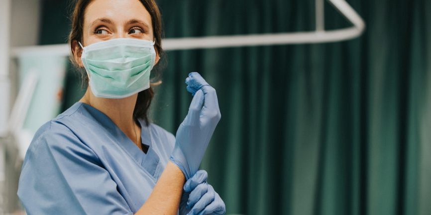 Nurse putting on glove in emergency room